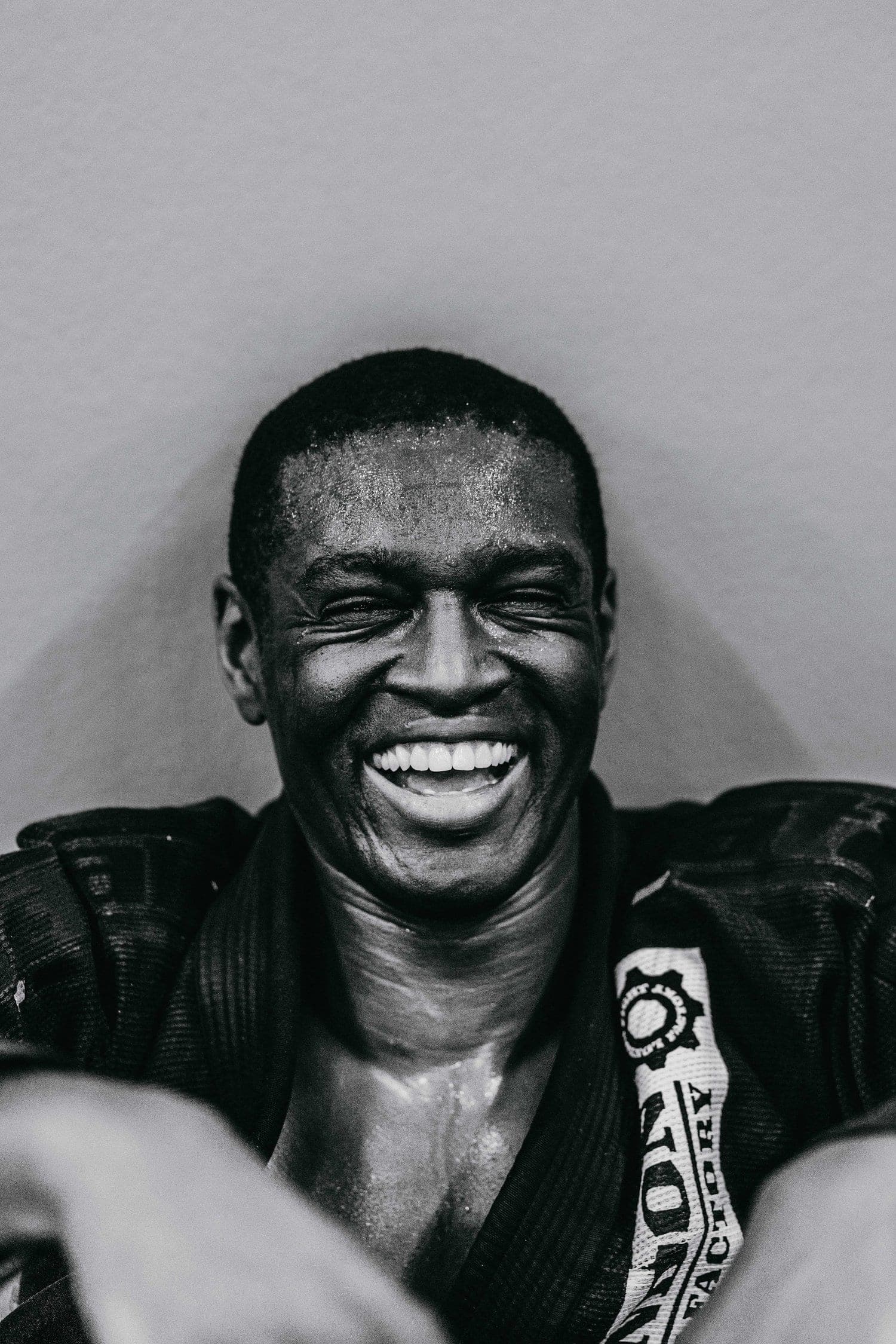 A black belt laughing against the wall after training