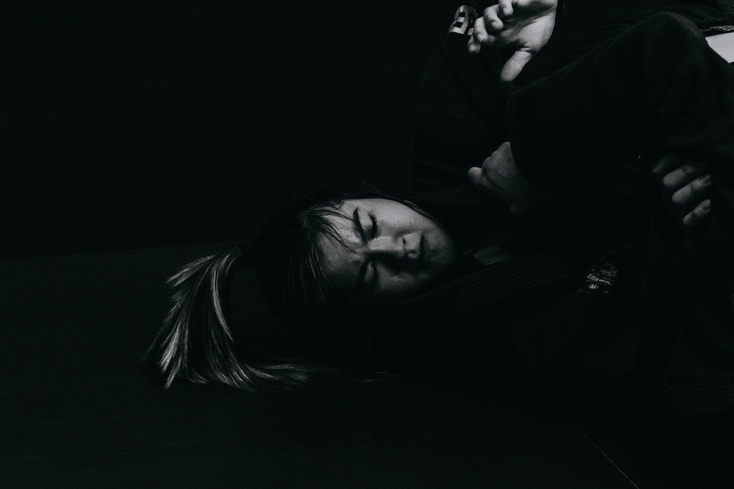 A grappler pinned on the mat in low light