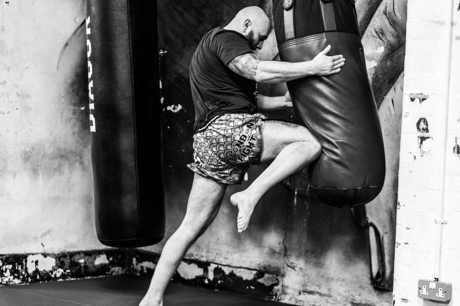 A Muay Thai fighter driving a knee into the bag