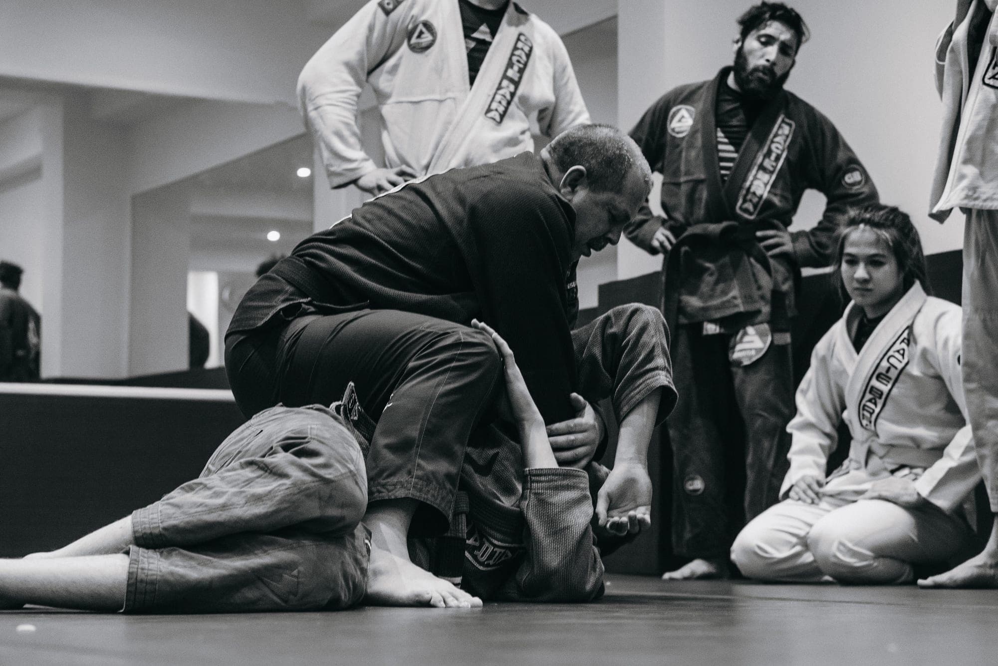 A coach working a position while the class watches from the mat